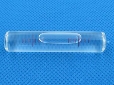There is a common glass tubular bubble level vial on a blue mat.