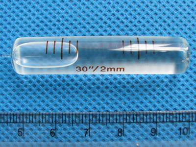 There is a glass tubular bubble level vials with a high sensitivity on a blue mat.