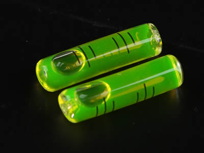 Two glass tubular bubble level vials with green water in and there are without tips on the top.