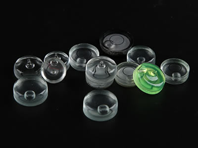 Several glass circular bubble levels in different sizes, colors and base types on black background.
